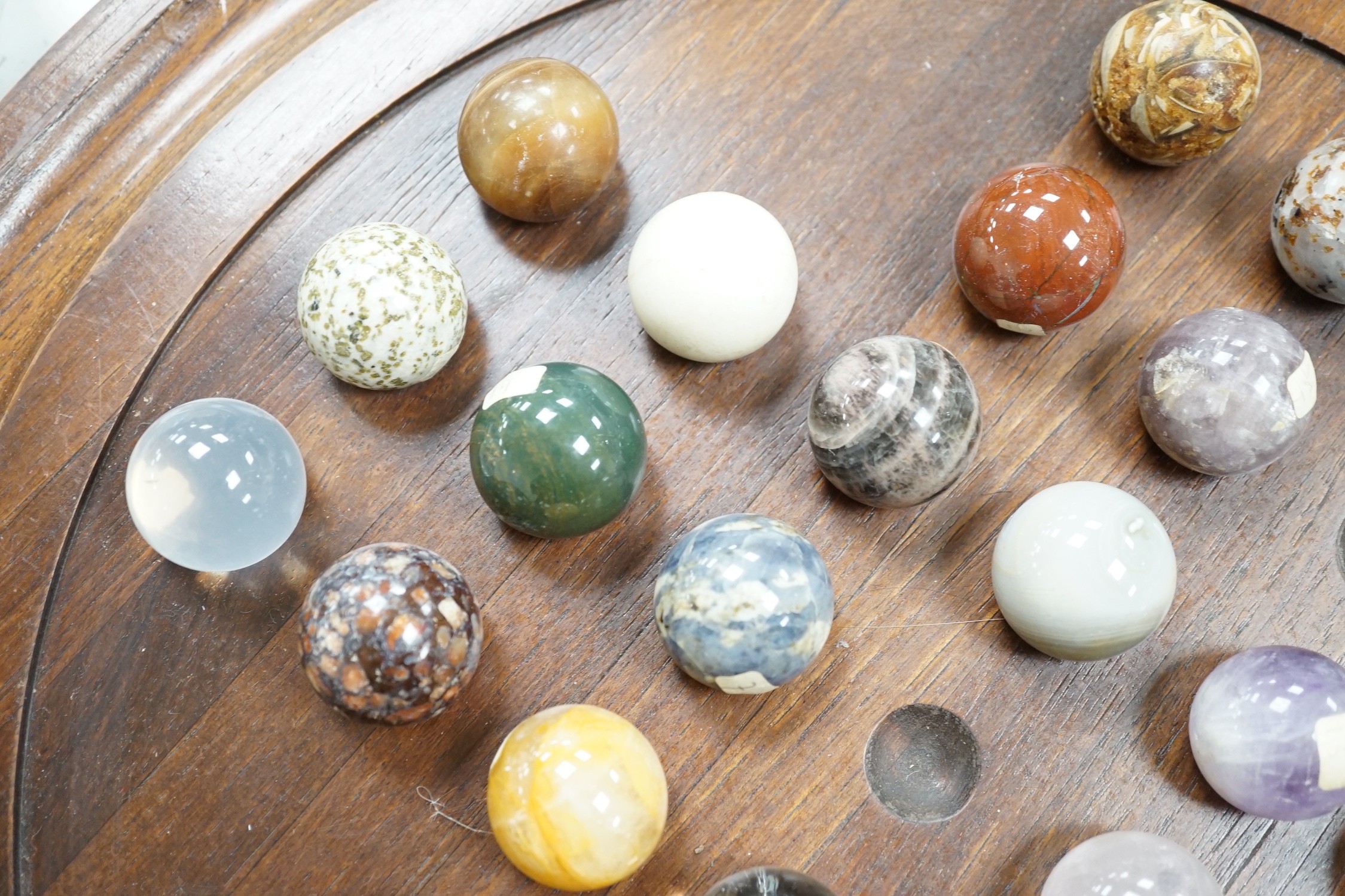 A large mahogany solitaire board with large specimen hardstone marbles, 42cm